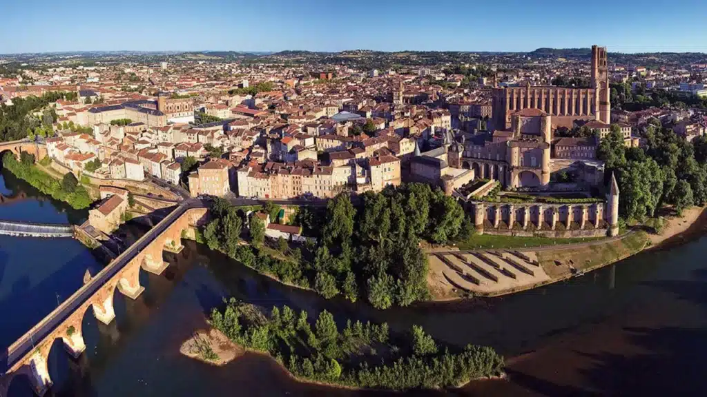 Albi : La splendeur de la Cathédrale Sainte-Cécile et du Tarn. Panorama aérien d'Albi. La Cathédrale Sainte-Cécile et le Palais de la Berbie surplombent le Tarn et le Pont Vieux.